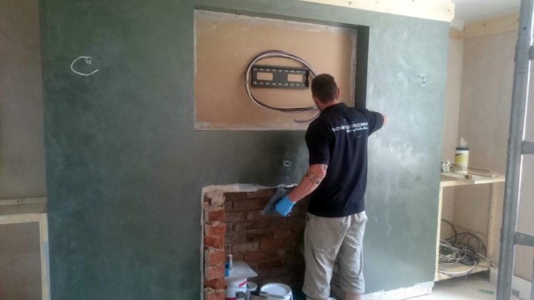 Plasterer trowelling Cadoro across the fire breast, brick hearth still open