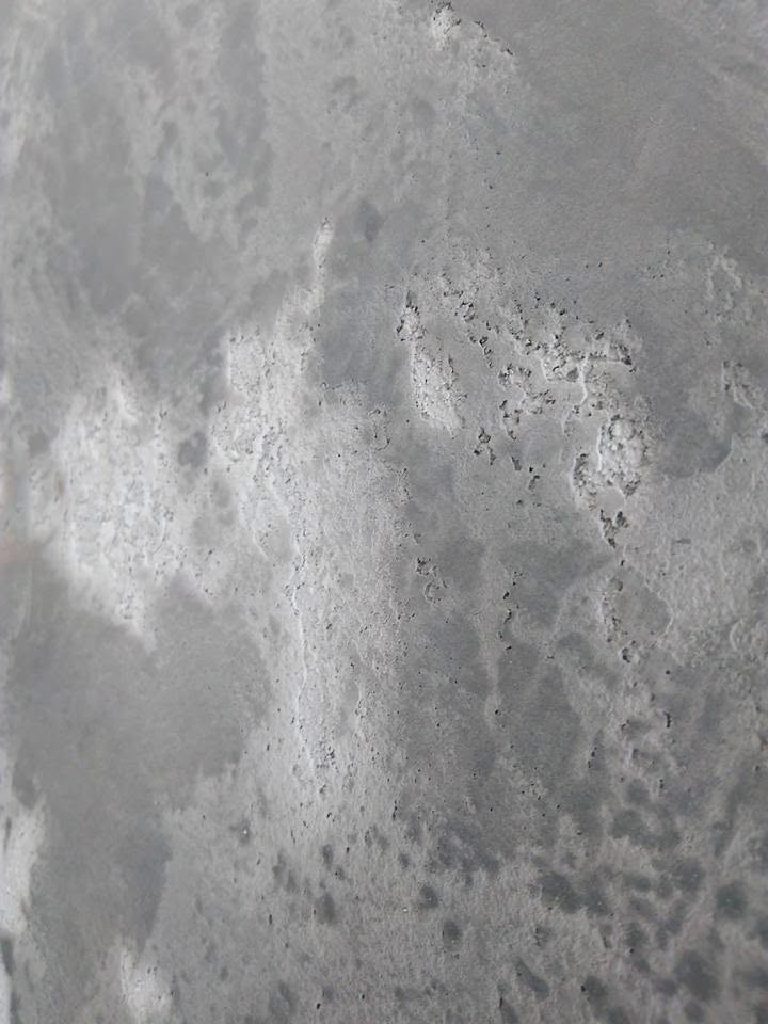 Weathered concrete effect close-up, mottled greys and pitted texture
