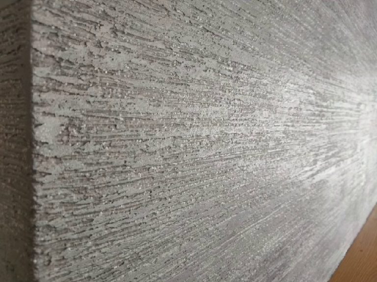 The grey plaster up close, long trowel strokes with fine glitter through them