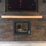 The fire and TV set flush into the black and bronze wall