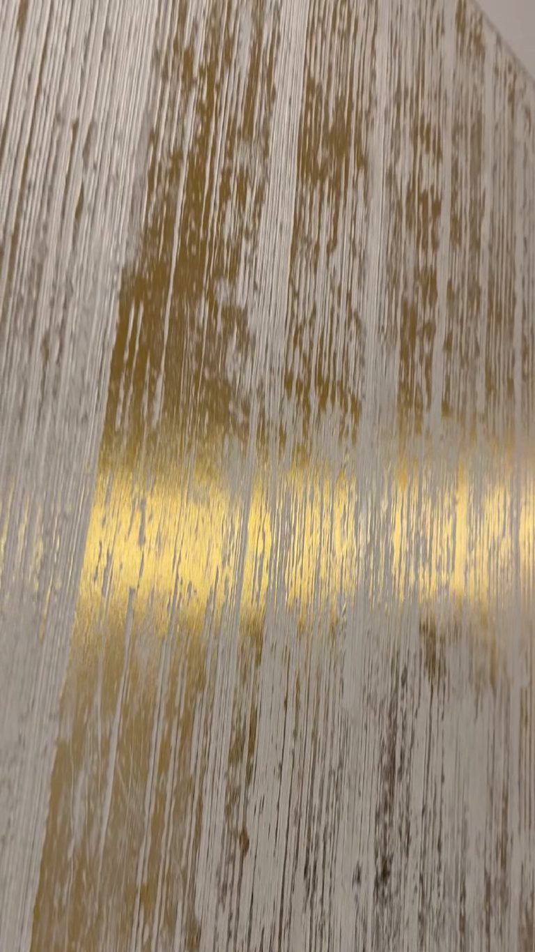 The panel from an angle, a band of reflected light running across the gold