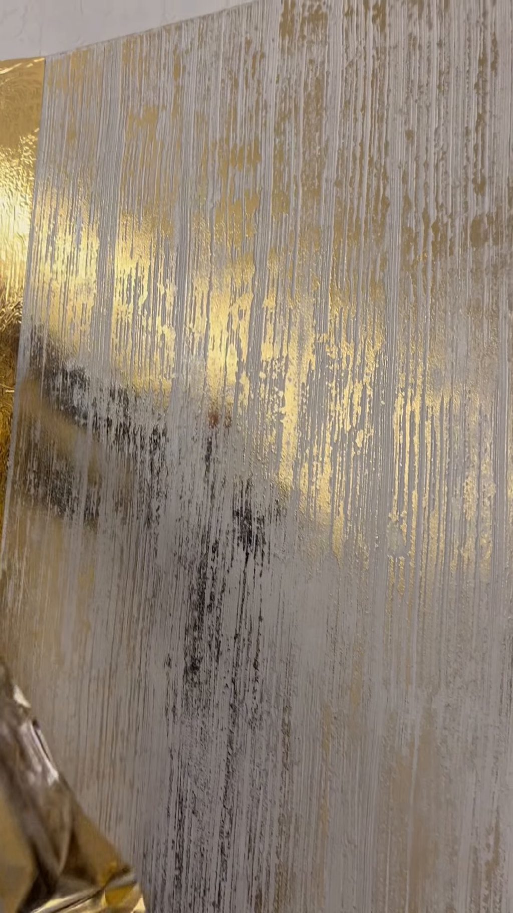 The top corner of the panel, foil lifting away at the left and the finish showing at the right