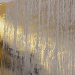 The top corner of the panel, foil lifting away at the left and the finish showing at the right