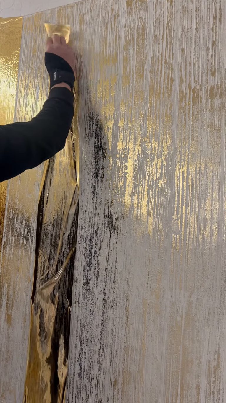 The foil sheet peeling back off the panel, leaving gold behind on the ridges