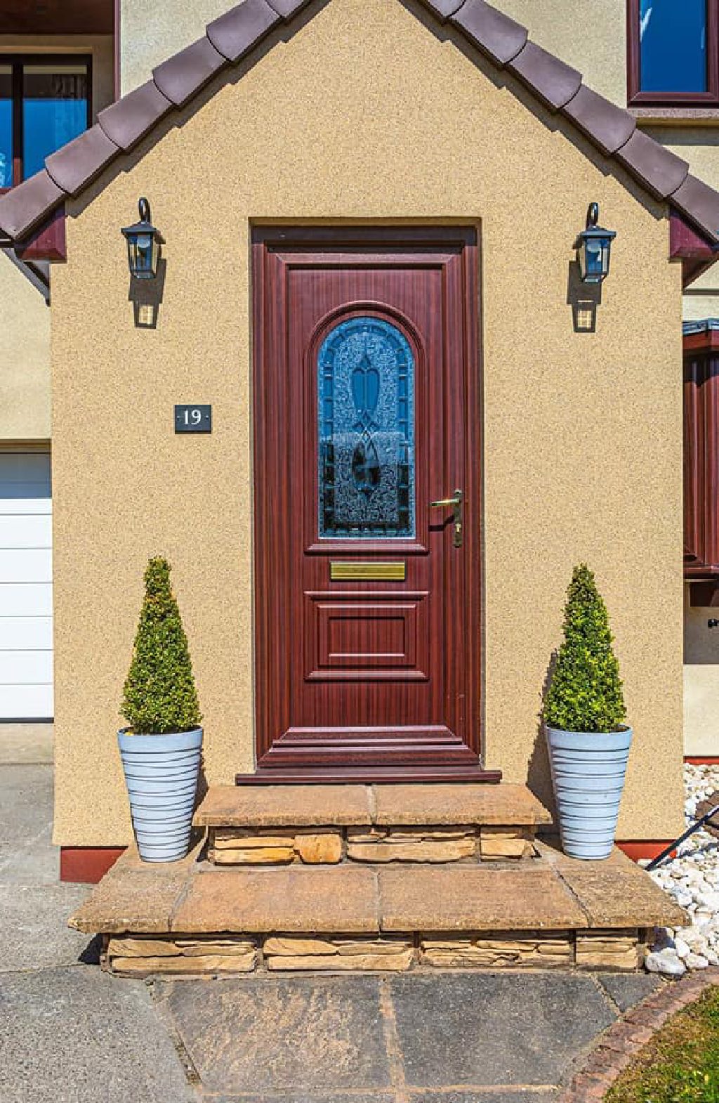 The finished front porch in daylight, sand-coloured Crystal Quartz walls either side of a dark red door