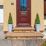 The finished front porch in daylight, sand-coloured Crystal Quartz walls either side of a dark red door