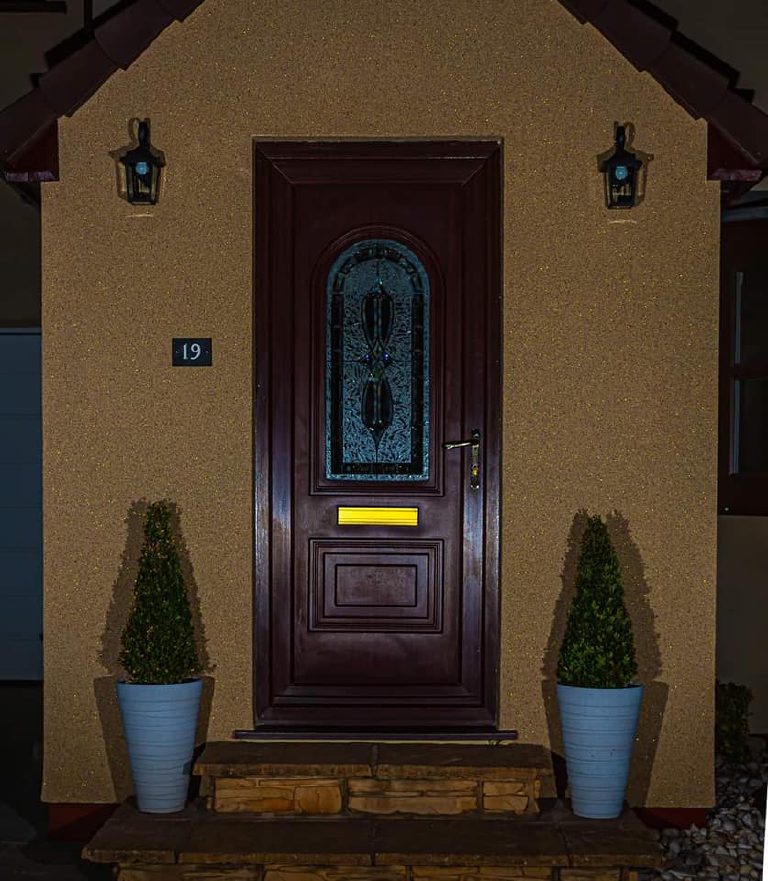 The porch at night seen straight on, both lanterns lit and the walls sparkling