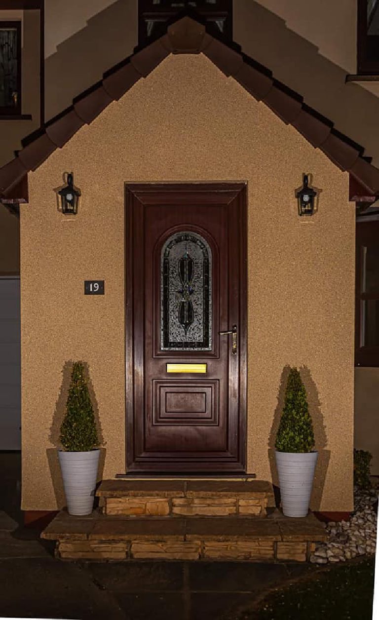 The whole porch gable after dark, lit by the two carriage lanterns