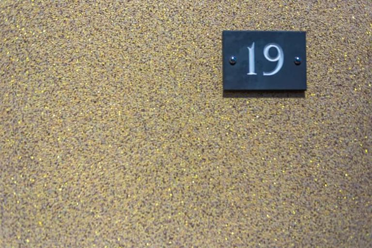 The slate house number fixed to the Crystal Quartz wall, gold flake scattered through the finish