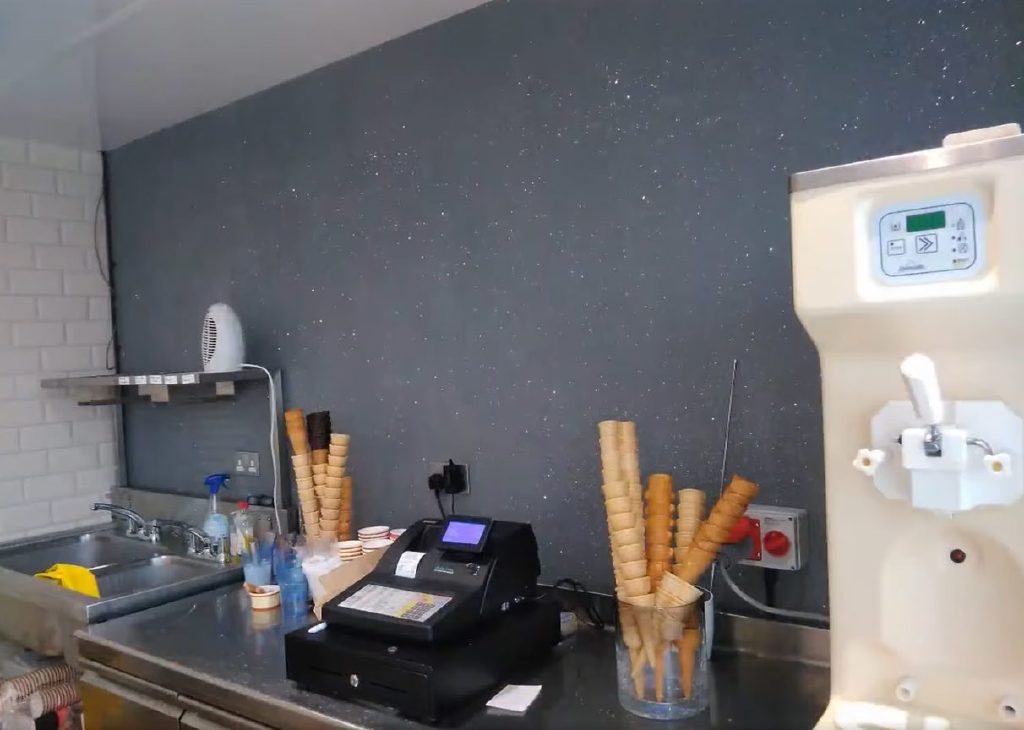 The charcoal glitter wall behind the counter, cones at the ready
