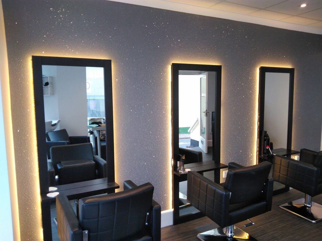 Three backlit mirrors set against the glitter feature wall