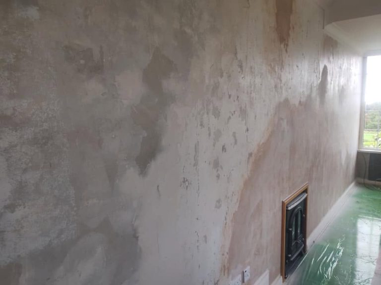 The living room wall before work, stripped back to patched plaster