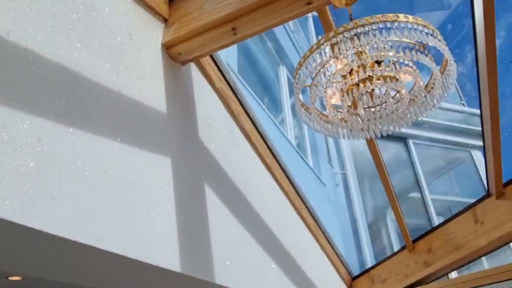 The crystal chandelier under the glazed roof, glitter wall lit up alongside it