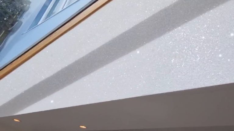 The wall lit at a low angle, sparkle on one side of the shadow line and plain white on the other