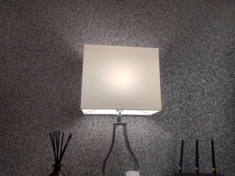 A wall light throwing a pool of light down the glitter finish