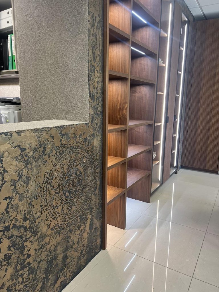 The bronze finish on the end of a display return, walnut open shelving alongside