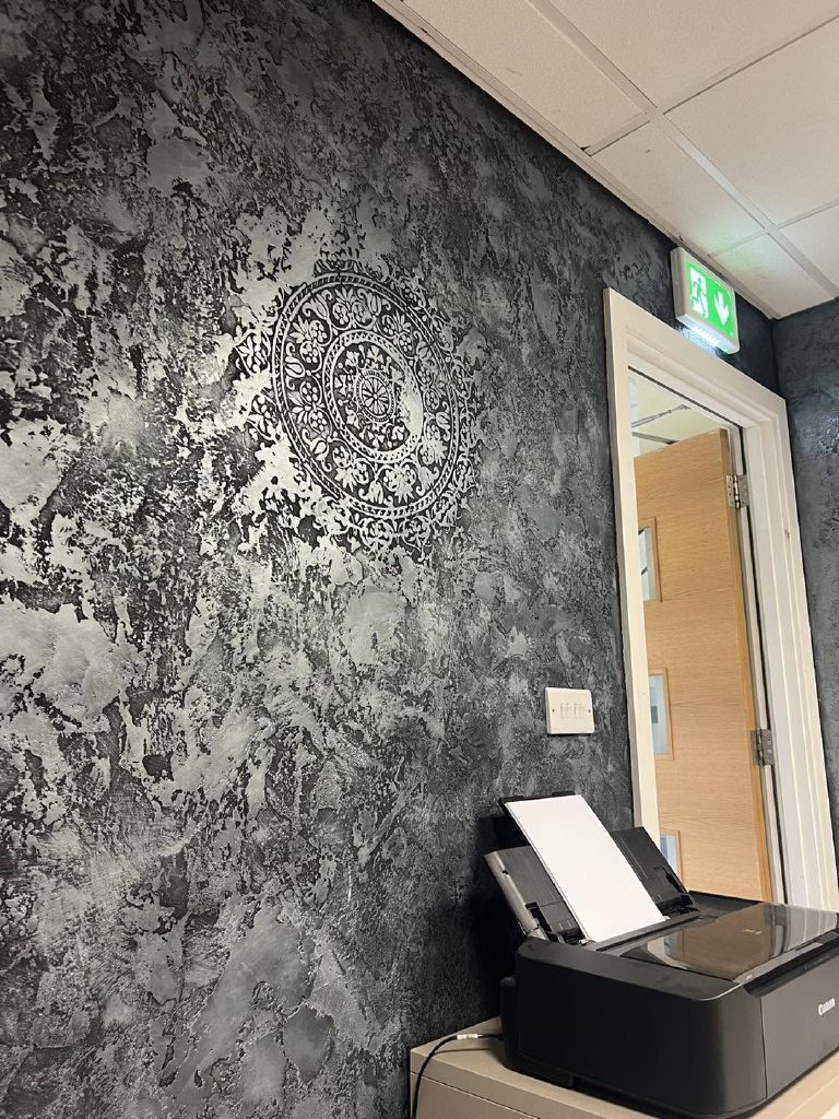 A silver-waxed wall with a stencilled medallion beside an oak door