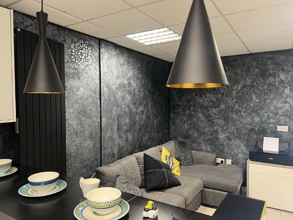 Black Marmorino with silver wax wrapping the showroom living area, stencilled medallions on two walls