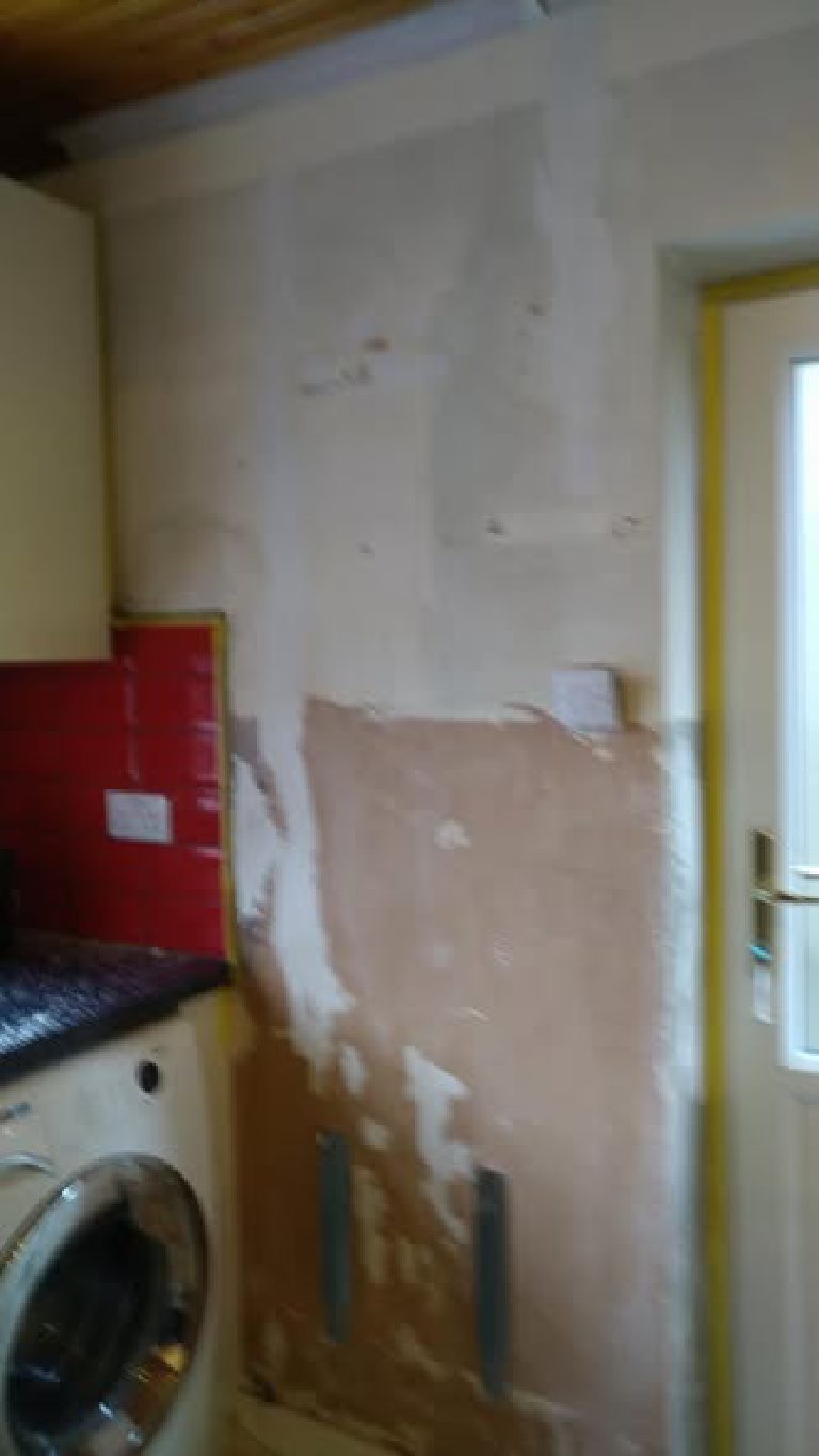 Bare patched plaster by the washing machine before coating