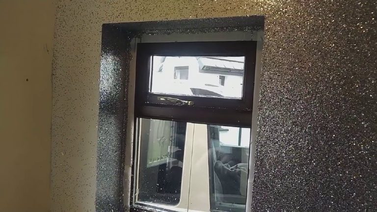 The window framed in gun metal glitter, bare wall still showing at the edge