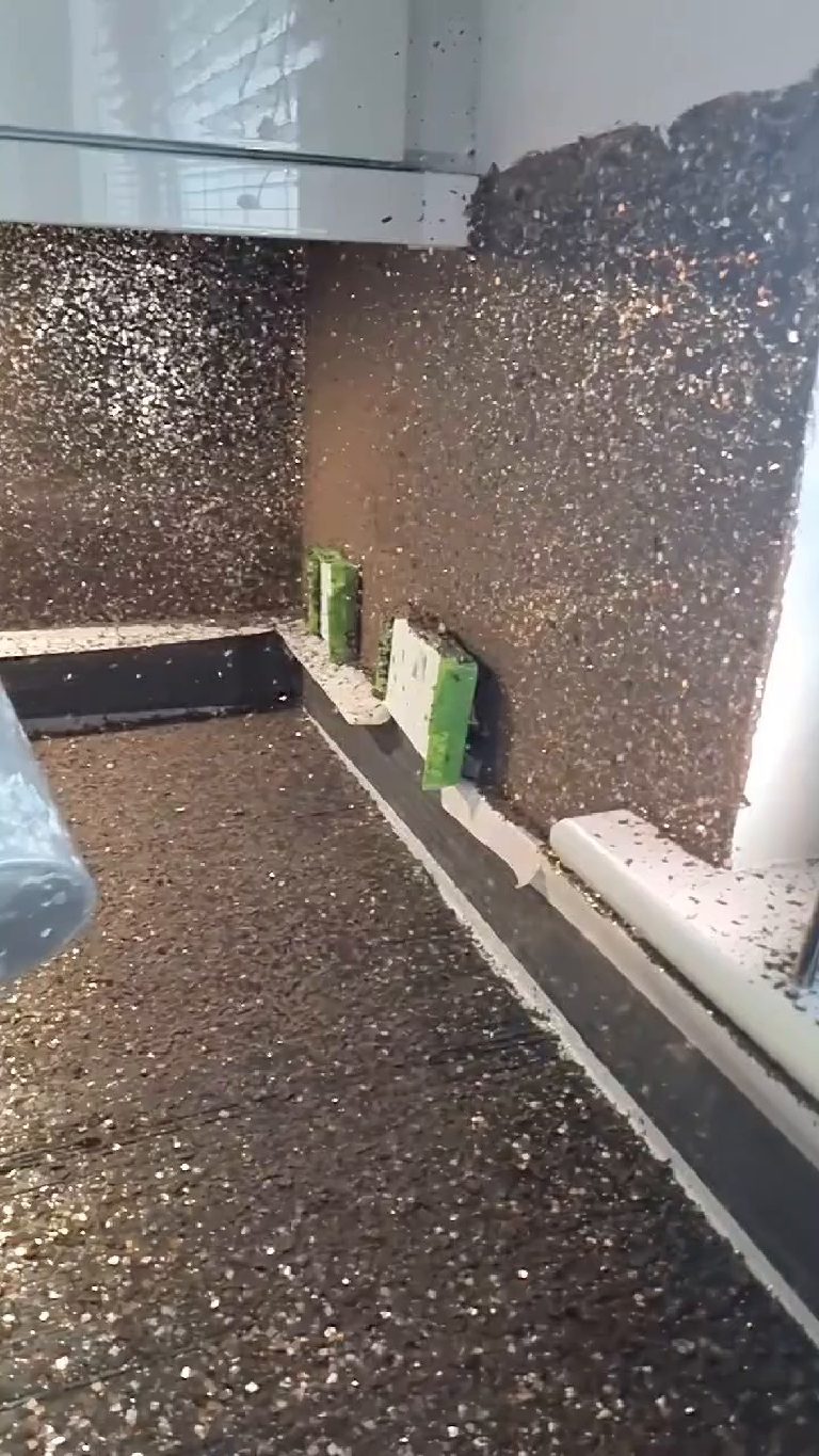 The wall almost fully covered in flake, with more still coming through the air