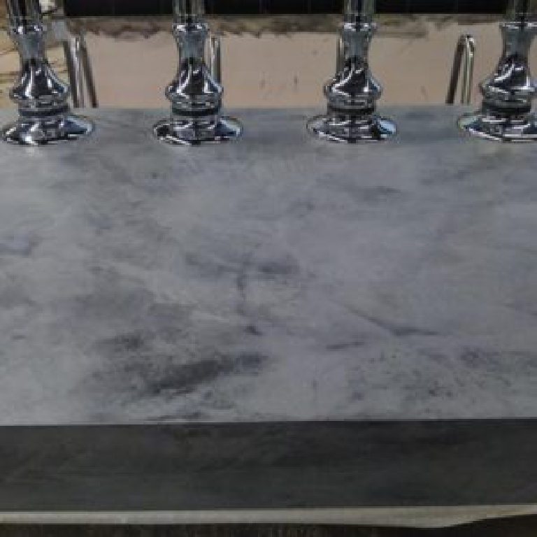 Grey MicroCement bar top taking shape around the chrome founts