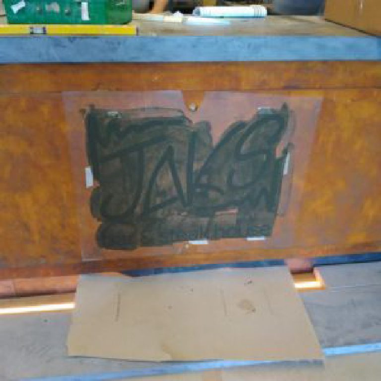 The JAK's logo stencil taped to the rust-effect bar panel
