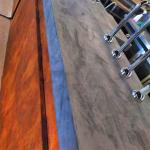 Rust-effect bar front meeting the grey MicroCement bar top with chrome founts
