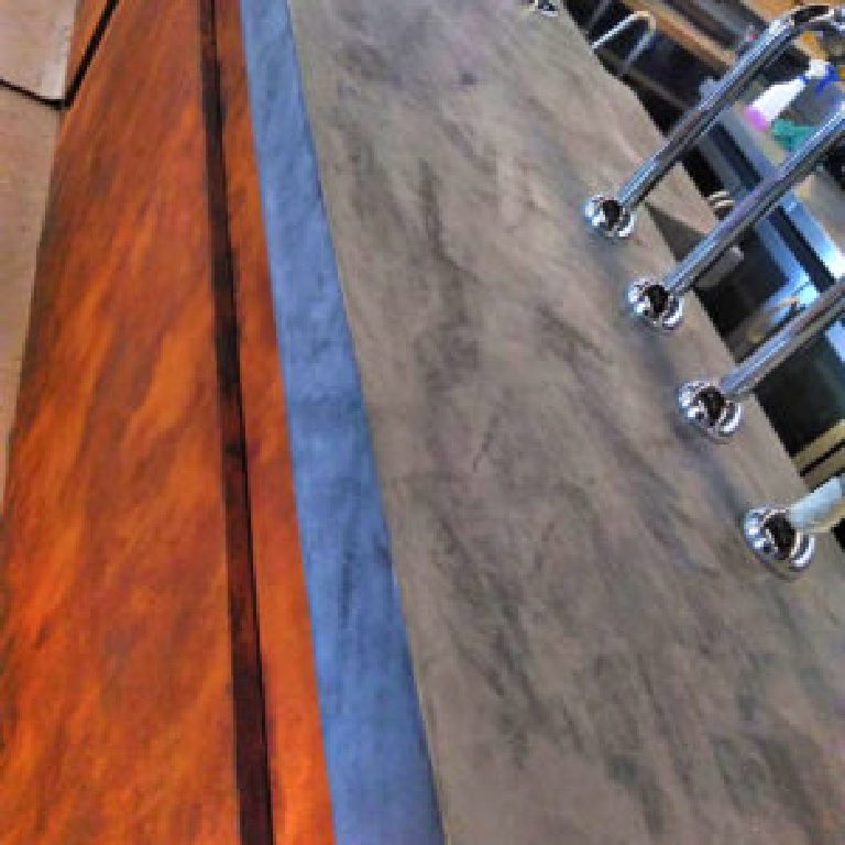 Rust-effect bar front meeting the grey MicroCement top with chrome founts