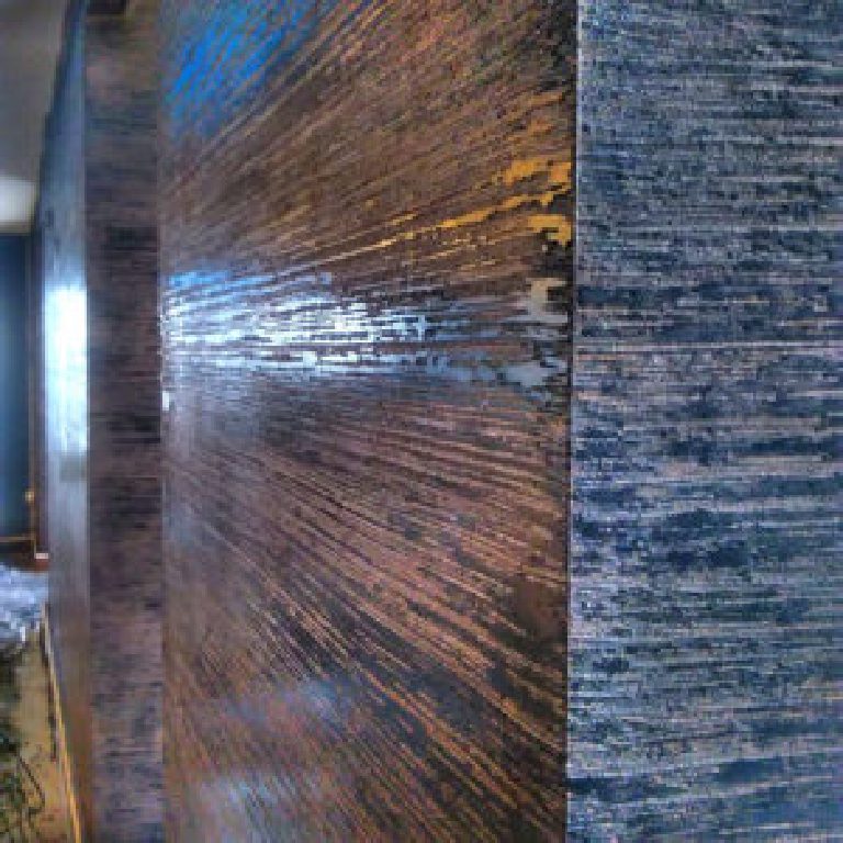 Corner where the dragged bronze finish meets the blue textured wall