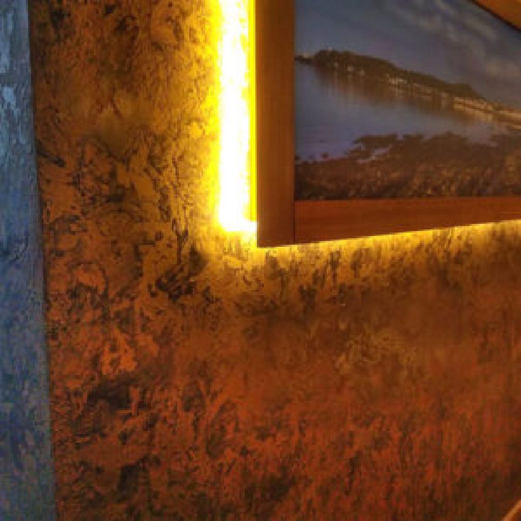 Copper patina wall glowing under a backlit print