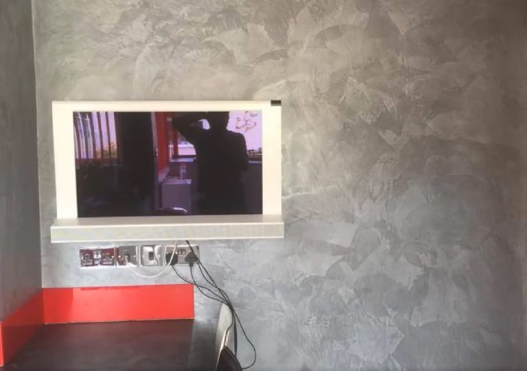 Close view of the recessed TV surrounded by grey Marmorino