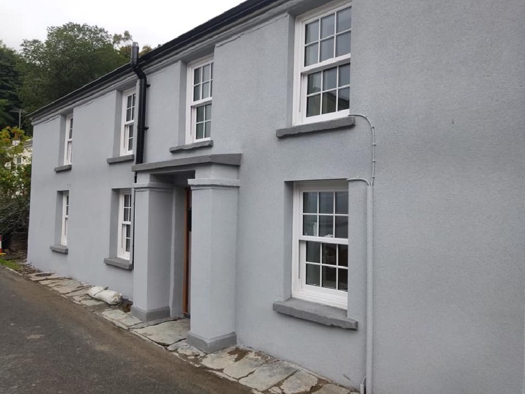 The finished front of the cottage in grey cork render, taken from the road below