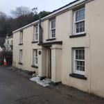 The same view before the work — tired cream render, streaked and stained, sandbags along the base