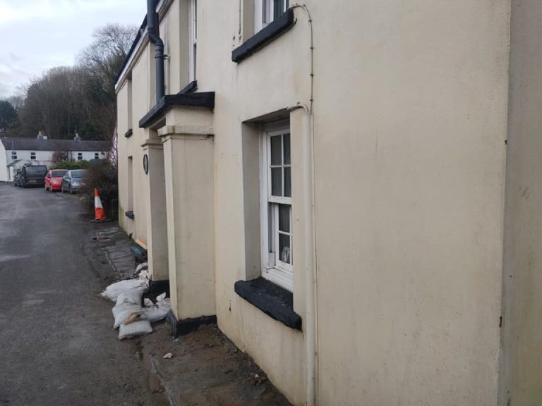 The front elevation before, seen at a sharp angle down the road, staining running down the wall