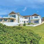 The finished house across the lawn — white render, glass balconies, blue sky