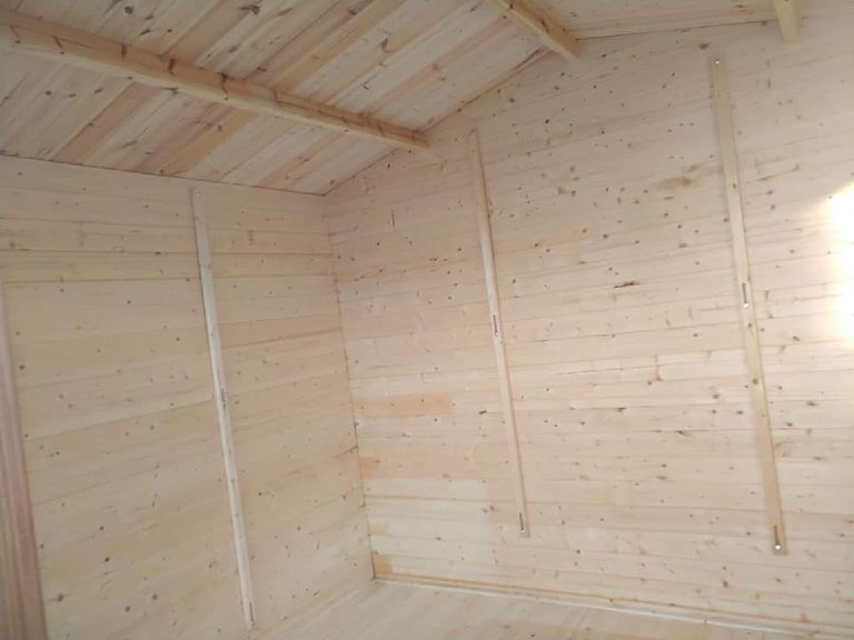 The bare pine boards inside the shed before spraying