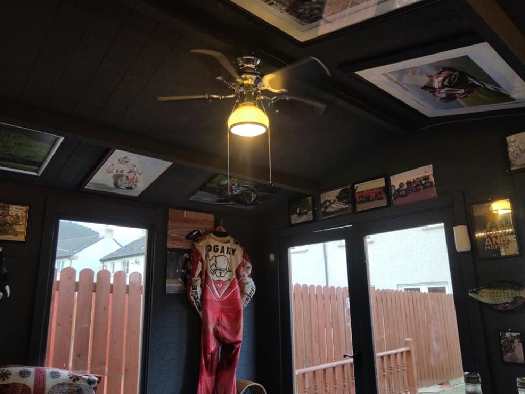 The finished man cave in use, with racing leathers, framed prints and a ceiling fan