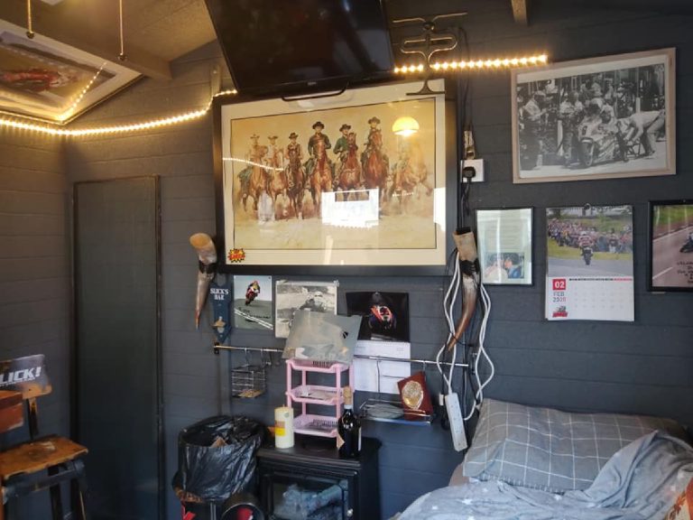 The other end of the man cave, with a television, framed prints and somewhere to sit