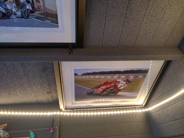 Framed prints and a warm LED strip against the sprayed cork wall