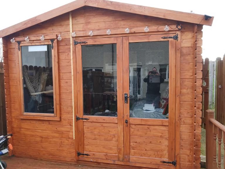 The timber garden shed outside before any work, with glazed double doors
