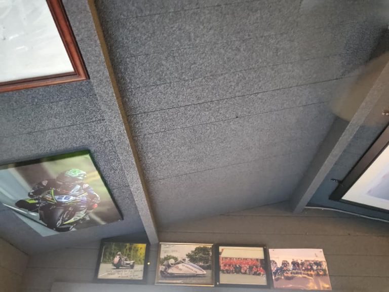 The sprayed cork ceiling running up the pitch, with framed prints below