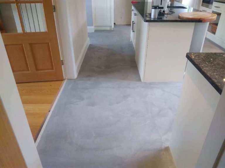 The first grey MicroCement coats going over the tiled floor