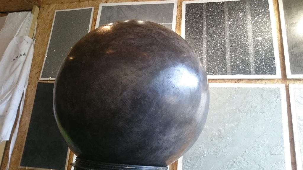 The finished slate-grey microcement sphere, polished to a sheen