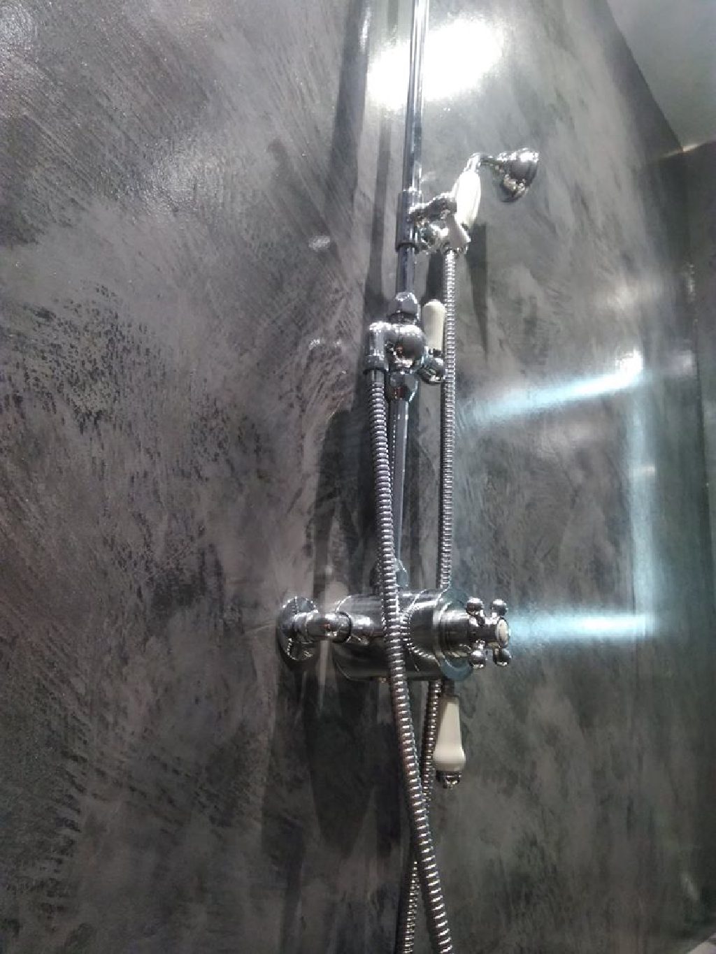 Traditional chrome shower fittings against polished charcoal MicroCement