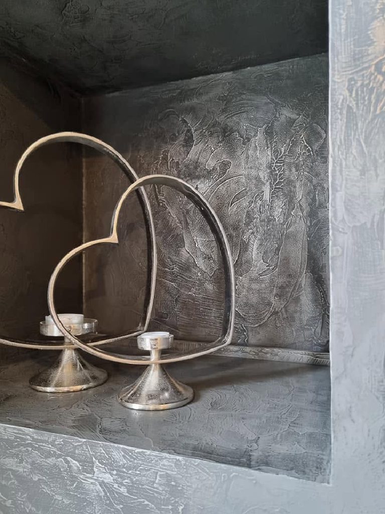 A nickel-finished recess with two silver heart tealight holders on the shelf