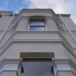 Looking up the front bay, repaired cornices and moulded window heads against the sky