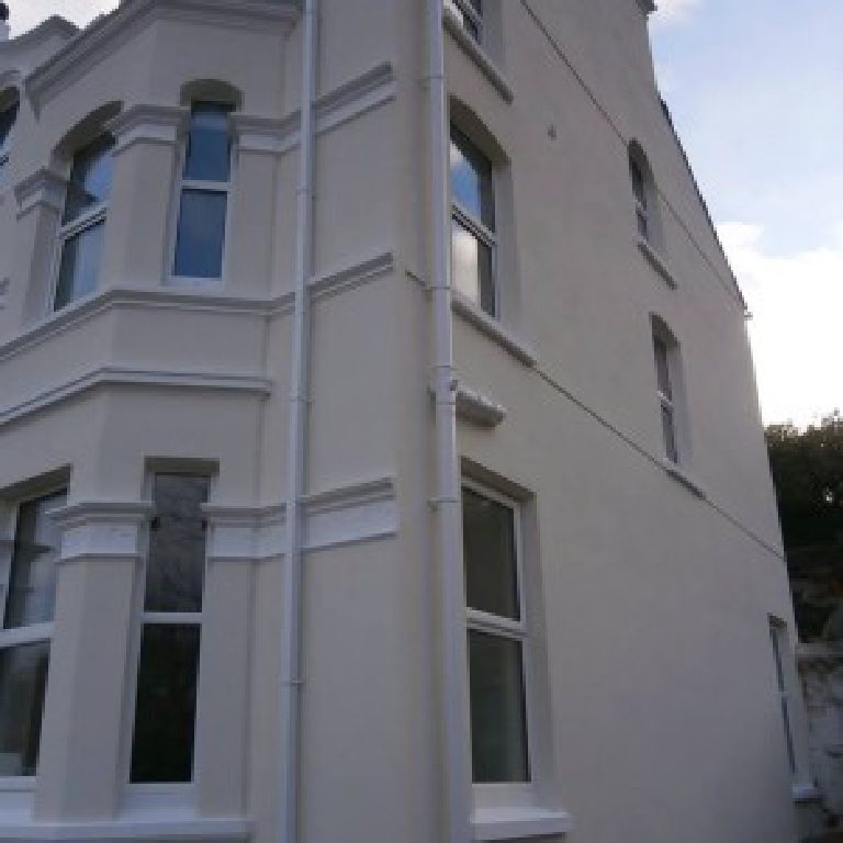 The front corner of the house, bay windows and rendered detail carried round