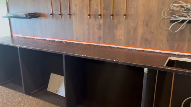 The back bar top finished, taps and copper pipework on the timber wall above it, tape still along the join