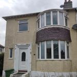 The same front before the work — old dash finish, patchy and discoloured, weeds along the base